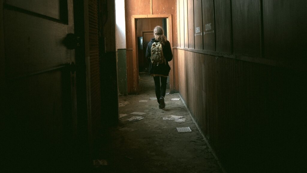 young woman walking down a corridor in an abandoned building